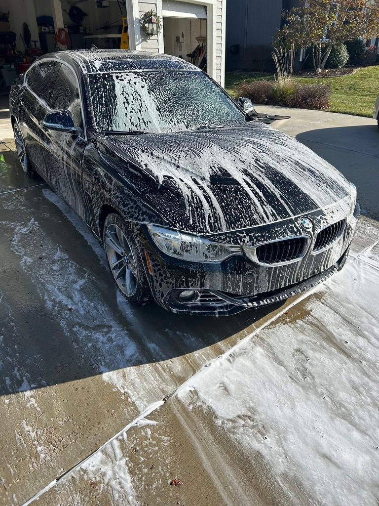 Black BMW 4 Series Gran Coupe covered in foam during a driveway wash