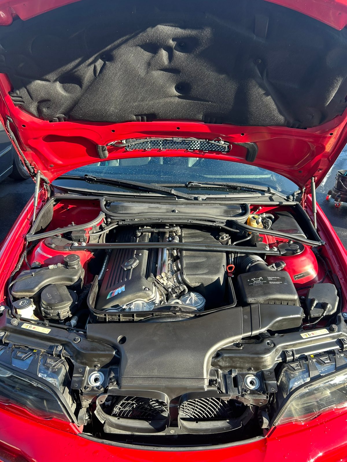 Clean engine bay of a red BMW M3 after an engine bay detail