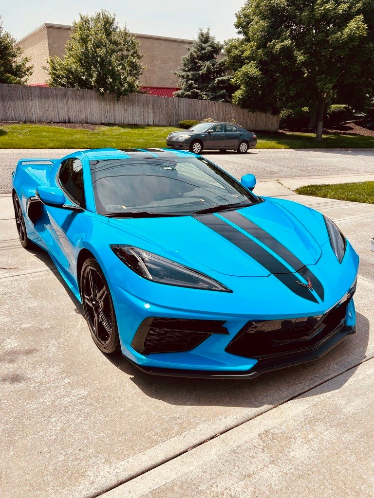 Blue Corvette with black stripes after a detail, parked in a driveway
