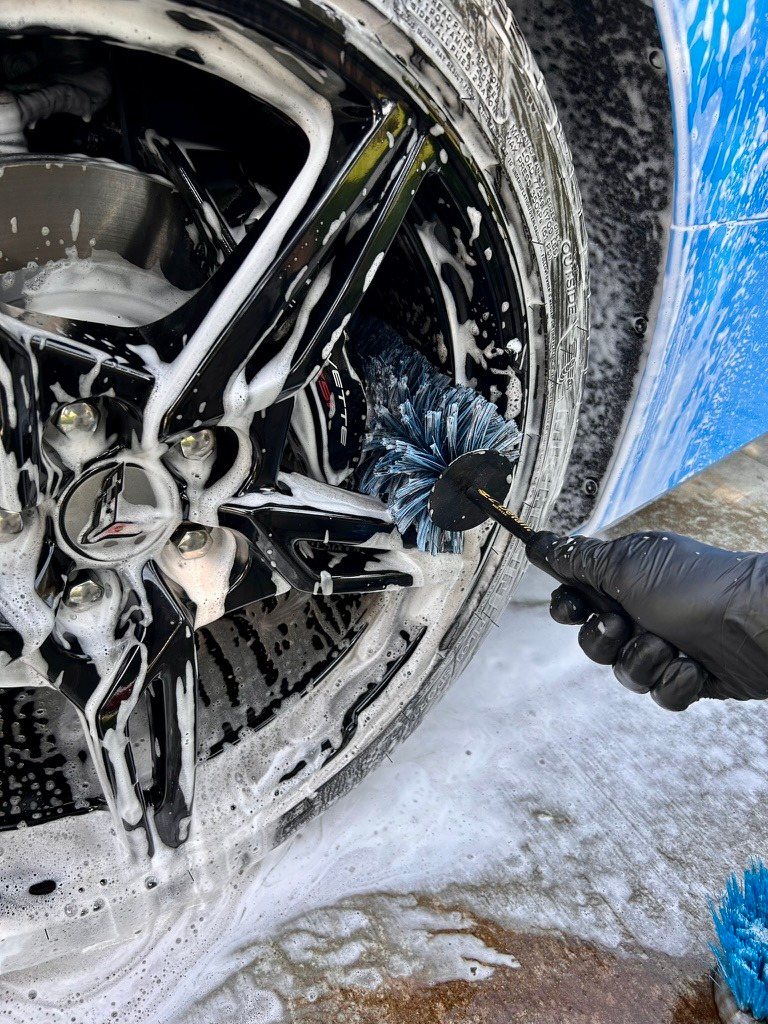 Cleaning a Corvette wheel with a brush and foam