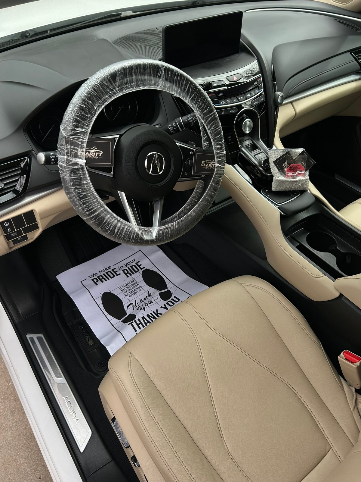 Acura RDX interior after a mobile interior detail, with a covered steering wheel and a paper floor mat