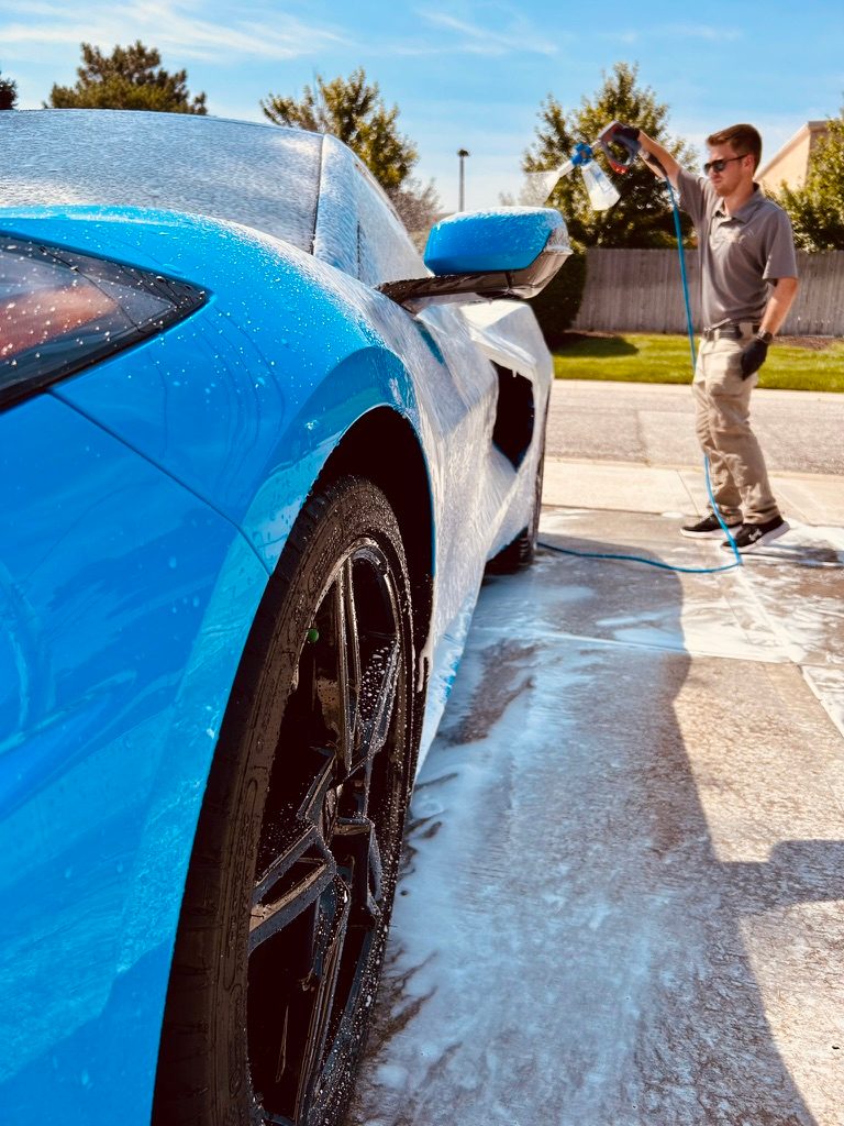 Sam foaming a blue Corvette during a mobile exterior detail