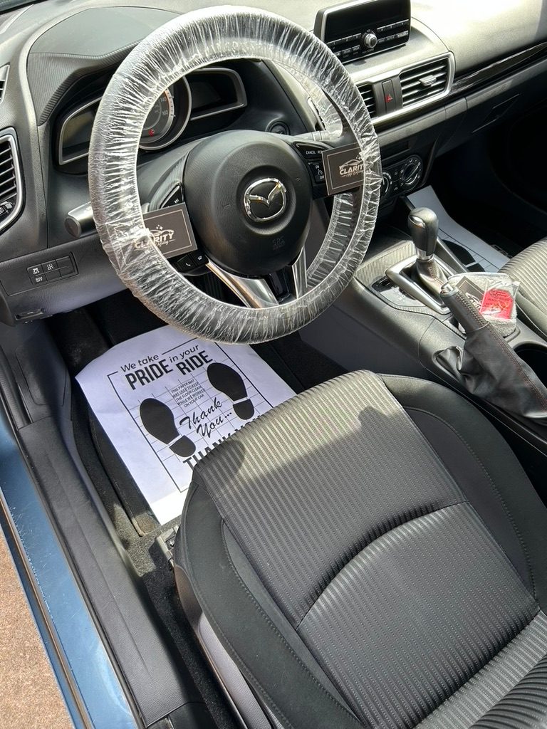 Mazda3 interior after a detail, with Clarity cards on the covered steering wheel and a paper floor mat