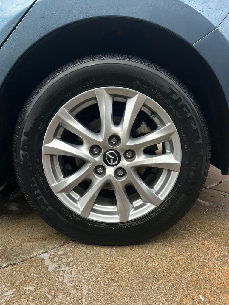 Clean silver Mazda wheel and dressed tire after a mobile exterior detail