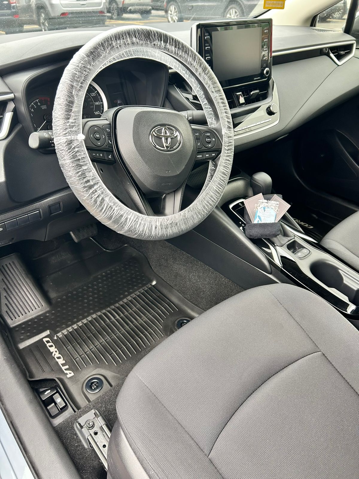 Toyota Corolla interior after a detail in Overland Park, with clean floor mats and a covered steering wheel